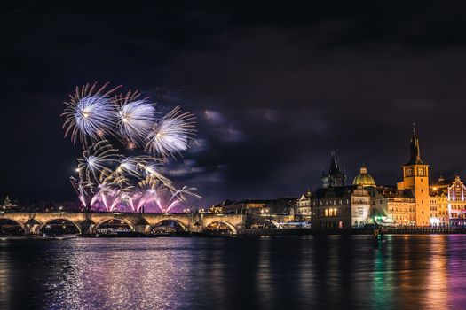 Beautiful fireworks above Charles bridge at night in Prague, historic center, Czech Republic, bautiful reflections in water.