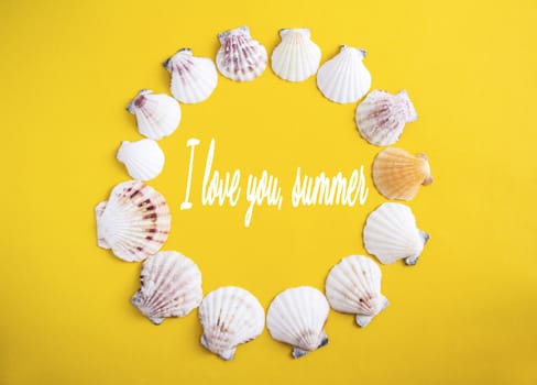 Circle of white seashells on yellow background with lattering I love you, summer