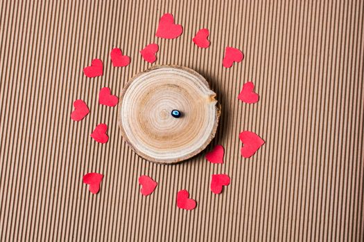 Bead on Piece of log with red paper hearts  on cardboard