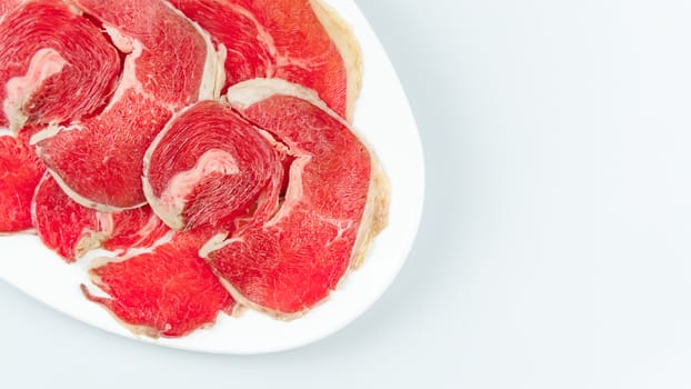 Top view of some raw beef on a plate over white background