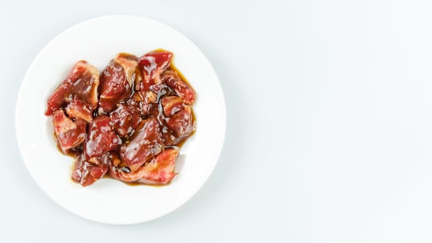 Top view of some raw beef with sauce on a plate over white background