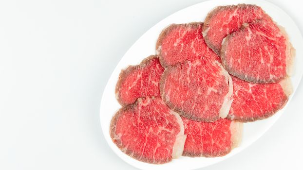 Top view of some raw beef on a plate over white background