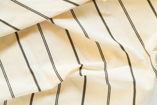 Beige linen fabric with black stripes, the texture of the fabric, the weaving industry or material for sewing
