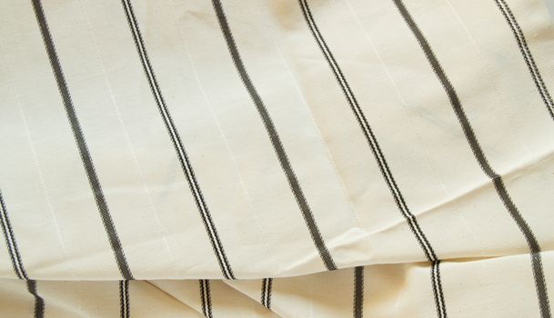 Beige linen fabric with black stripes, the texture of the fabric, the weaving industry or material for sewing