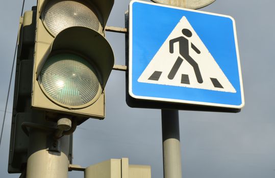 sign pedestrian crossing and traffic light on the background of the cloudy sky, the concept of road safety.