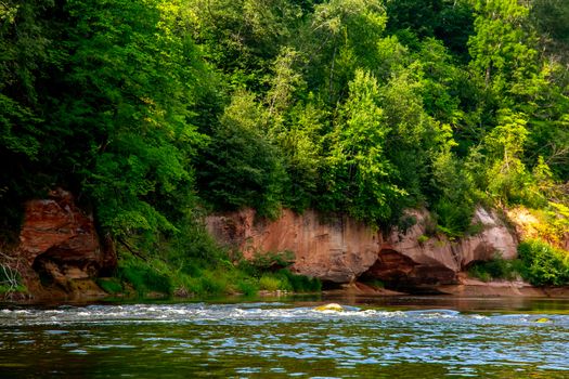 Landscape of cliff with cave near the river Gauja and forest. Gauja is the longest river in Latvia, which is located only in the territory of Latvia. 