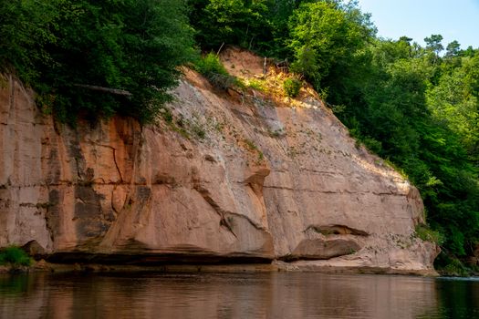 Landscape of cliff with cave near the river Gauja and forest. Gauja is the longest river in Latvia, which is located only in the territory of Latvia.