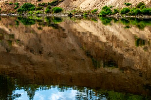 Landscape with cliff near the river Gauja and reflection in water. Gauja is the longest river in Latvia, which is located only in the territory of Latvia. 