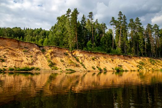 Landscape with cliff near the river Gauja, sky and trees reflection in water. The Gauja is the longest river in Latvia, which is located only in the territory of Latvia. 