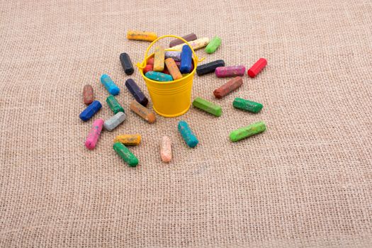 Crayons of various color in a bucket on a canvas