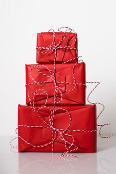 Christmas gift boxes wrapped in red paper and bow of dtriped rope on white background