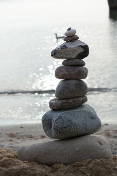 Stones stacked on top of each other on the beach with sea view in the background