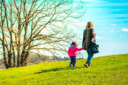 mom and daughter walk together outside .