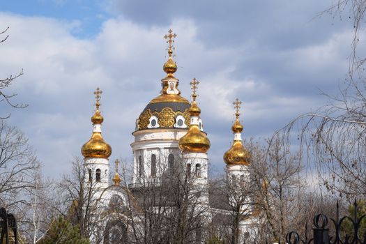 Golden domes of the Orthodox Church in the trees autumn landscape