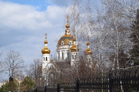 Golden domes of the Orthodox Church in the trees autumn landscape