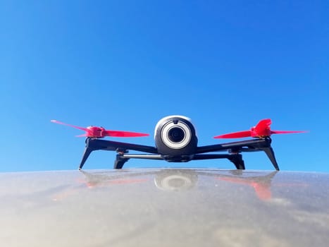 quadcopter with red turbine stands on the surface against the blue sky.