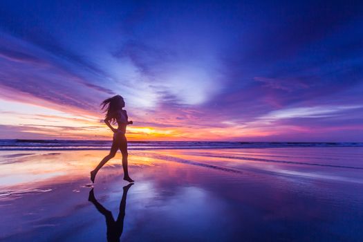 Beautiful sporty girl in bikini run on the seashore at sunset