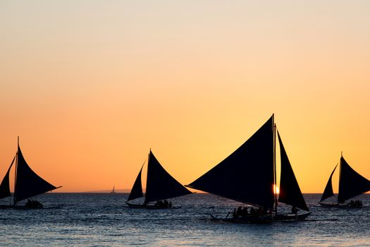 Sailing boats silhouette at orange sunset background