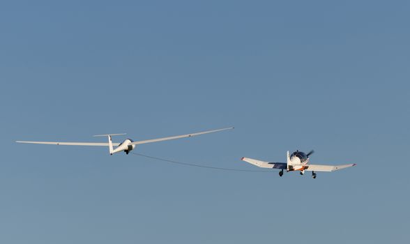 White modern glider which is increased by a small motorized sport airplane
