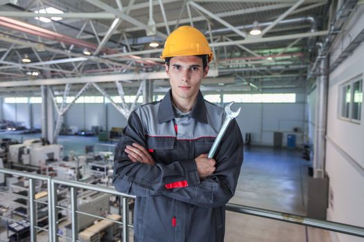 Young worker in hardhat with wrench at CNC factory