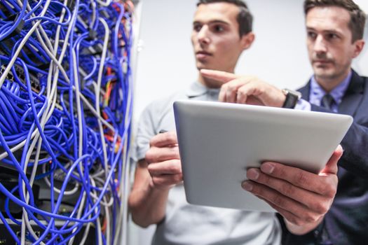 Engeneer and business man in network server room with digital tablet