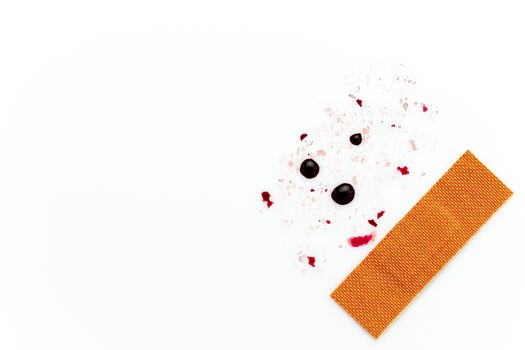 Brown wound plaster and droplets of fake blood on a white background. Copy space for text or articles. Concepts of health and medicine.