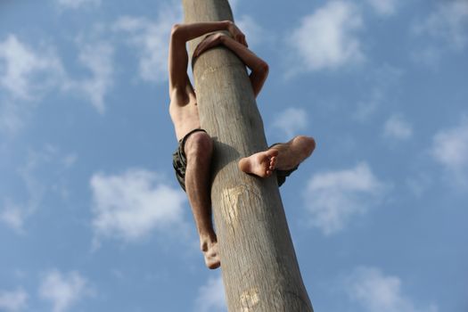 A man climbs on a pillar. Traditional carnival festival
