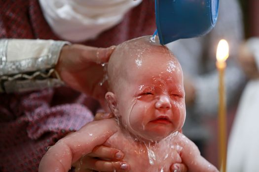 The rite of Orthodox baptism. The child is watered with water. Baptism of the newborn