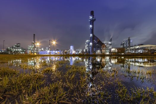 Reflection of the panorama of a refinery and its chimney during the sunset blue hour moment at Rotterdam, Netherlands