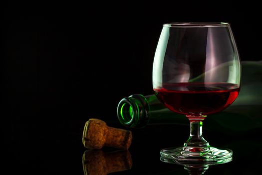 Red wine in glass and bottles on the table in darkness background. Copy space for text or articles.