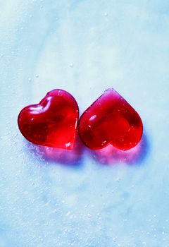 Valentines Day greeting card. Two red hearts in blue frozen water with free space