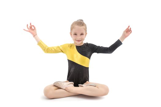 Little child girl gymnast sitting in yoga position isolated on white