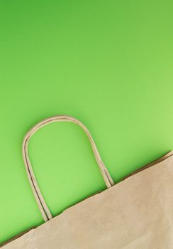 Concept of zero waste, reusable paper bag for shopping, free plastic, green background, top view, vertical photo