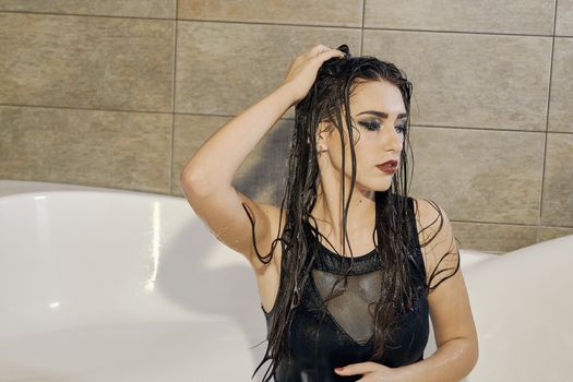 Young woman portrait with dripping smeared makeup dressed in the black bathing suit posing in the bathroom. Conceptual fashion photography for design. Young woman for lifestyle design.