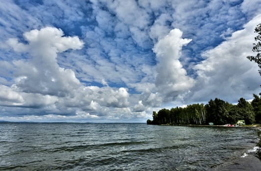 gray and white cumulonimbus clouds against the blue sky over the lake