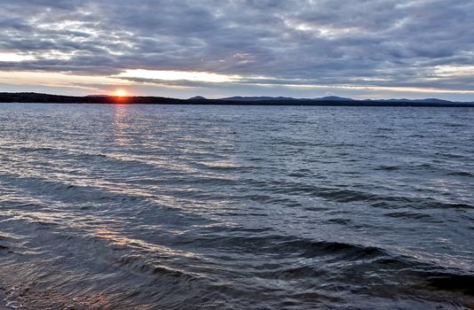 the evening sky over the lake, silhouettes of clouds illuminated by the sun