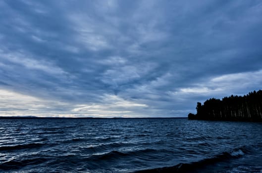 dark blue evening cloudy sky over the lake, wind, waves, heavy Shine of water