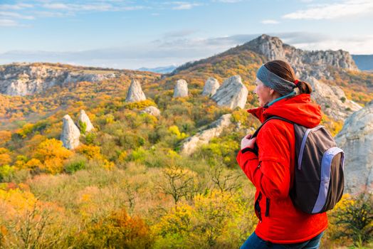 portrait of a happy traveler with a backpack in the mountains admiring the autumn forest