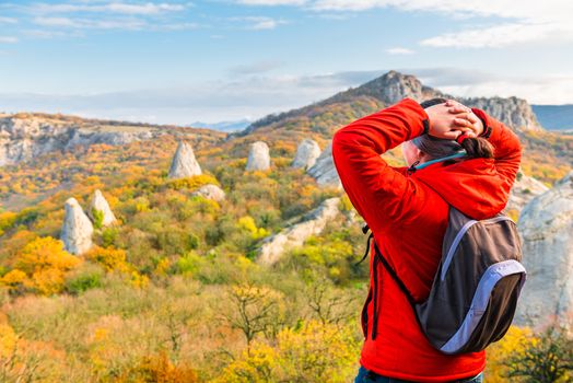 traveler with a backpack in the mountains admires the autumn forest