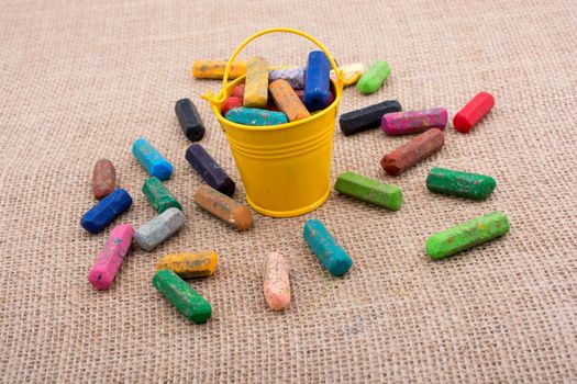 Crayons of various color in a bucket on a canvas