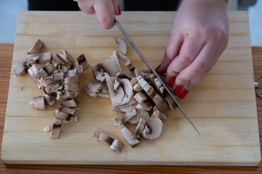 Woman cutting mushrooms on wooden board