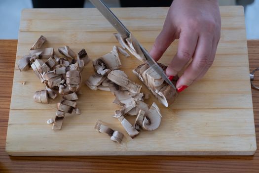 Woman cutting mushrooms on wooden board