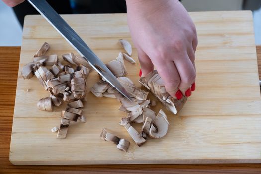 Woman cutting mushrooms on wooden board