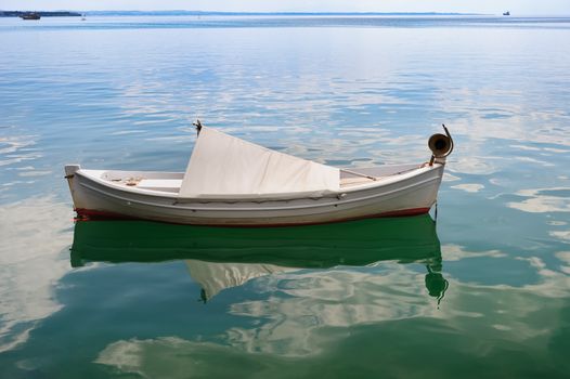 Very small white fishing boat at sea surface