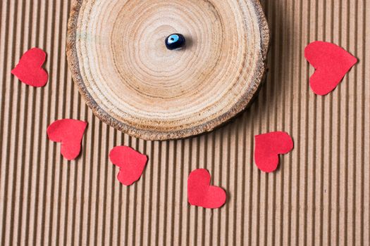 Bead on Piece of log with red paper hearts  on cardboard