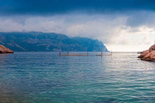 Gloomy dramatic rain clouds over the calm sea and mountains, picturesque landscape