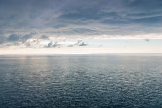 The surface of the sea with a slight ripple, a view of the horizon and heavy black rain clouds a beautiful landscape