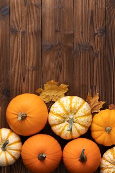 Many colorful pumpkins and dry maple leaves frame on wooden background with copy space , autumn harvest , Halloween or Thanksgiving concept