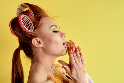 Young redhead woman with shugaring paste on her hands, face, body and chest. Young redhead woman with hair curlers. Advertising concept of shugaring paste. Skin care concept with copyspace.