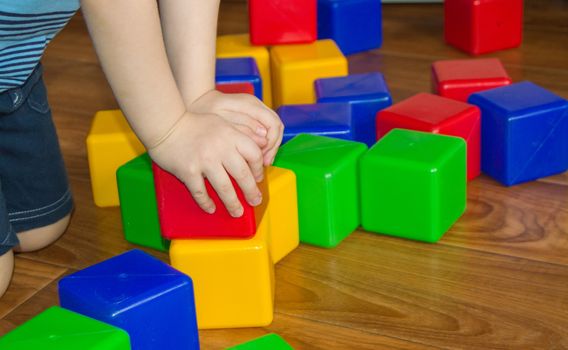 A small child playing with colorful cubes builds a tower, the concept of early education preparation for the development of the school.